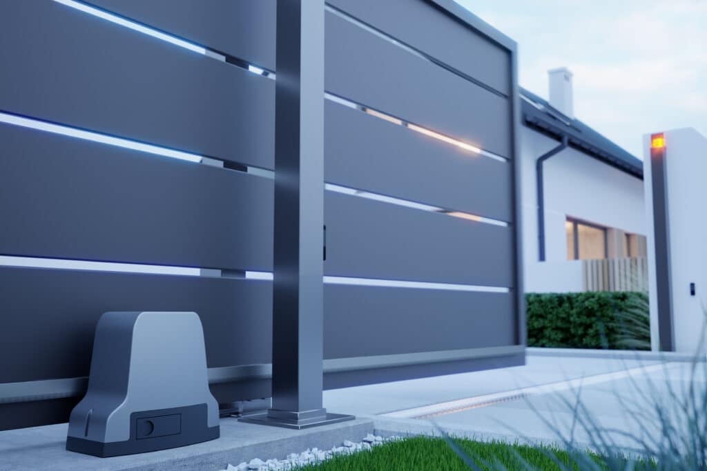 Portail coulissant automatique gris moderne avec lumières LED bleues et oranges, motorisation au sol, devant une maison contemporaine.